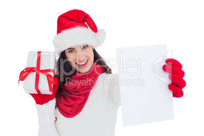 Festive brunette holding gift and showing paper
