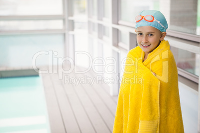 Cute little girl standing poolside wrapped in towel