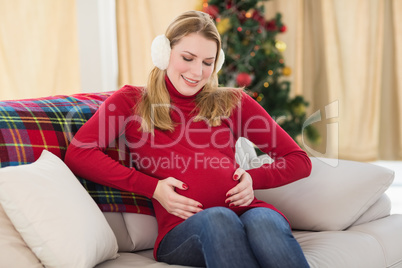 Beautiful pregnant woman holding her belly sitting on couch