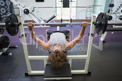 Young muscular man lifting barbell in gym