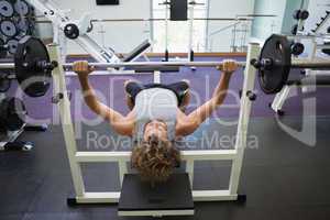 Young muscular man lifting barbell in gym