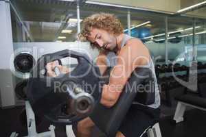 Side view of muscular man lifting barbell in gym