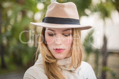 Pretty blonde woman with hat posing while looking down