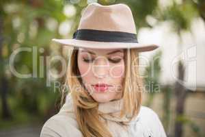 Pretty blonde woman with hat posing while looking down