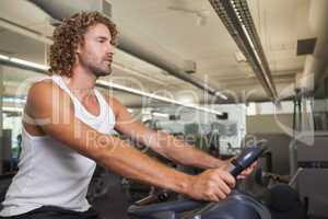 Side view of man working out on exercise bike at gym