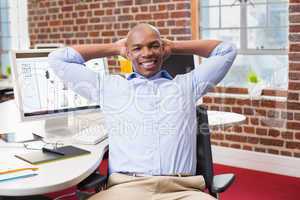 Businessman sitting with hands behind head in office