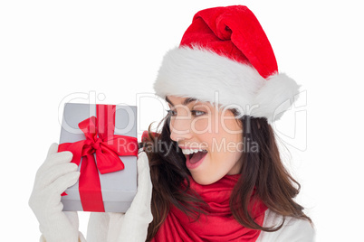 Astonished brunette in santa hat showing gift