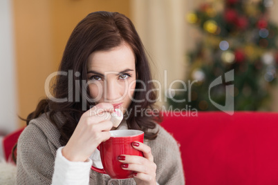 Brunette holding mug and eating marshmallow at christmas