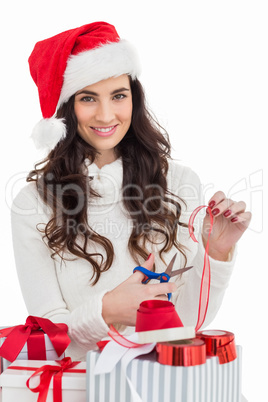 Smiling brunette in santa hat packing gifts