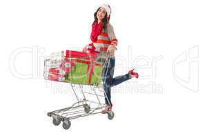 Festive brunette pushing trolley full of gifts