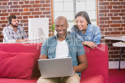 Casual colleagues using laptop on couch Casual colleagues using laptop on couch