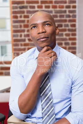 Thoughtful businessman looking up in office