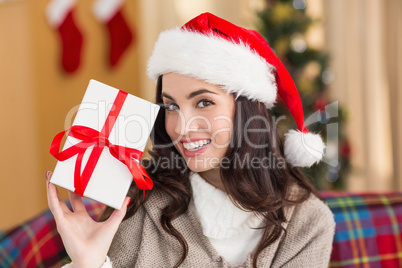 Festive brunette showing gift at christmas