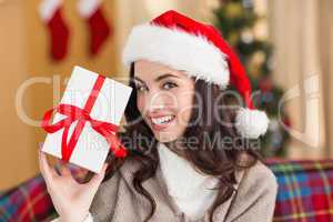 Festive brunette showing gift at christmas