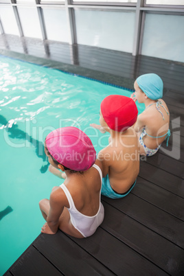 Cute swimming class sitting poolside