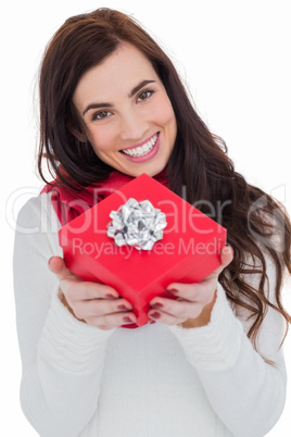 Happy brunette showing red gift with a bow
