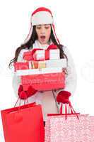 Surprised brunette in winter clothes holding many gifts and shop