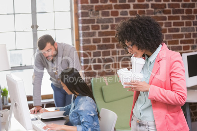Executives using computer with woman holding disposable cups