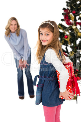 Little girl hiding christmas gift from mother