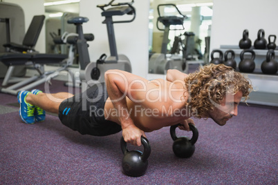 Man doing push ups with kettle bells in gym