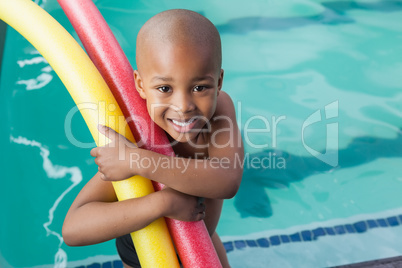 Cute little boy holding foam rollers by the pool