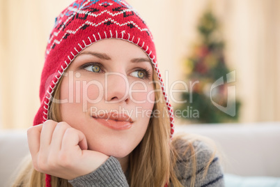 Woman in winter hat thinking with head on hand