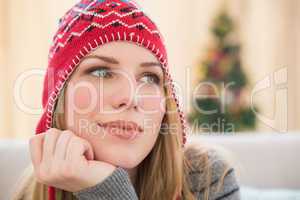 Woman in winter hat thinking with head on hand