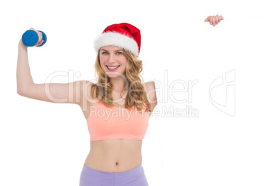 Festive fit blonde smiling at camera holding poster