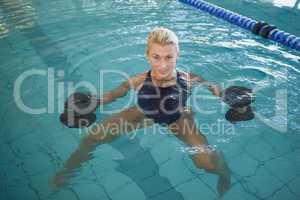 Female swimmer working out with foam dumbbells in swimming pool