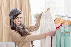 Smiling shopping brunette looking at dress