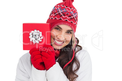 Festive brunette in winter clothes showing red gift