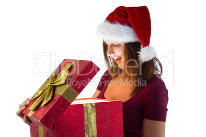 Pretty woman in santa hat opening a gift smiling at it