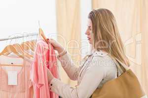 Pretty blonde looking at clothes on rail