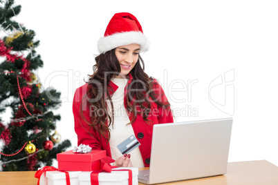 Pretty brunette in santa hat shopping online with laptop