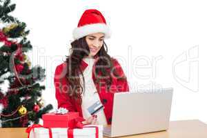 Pretty brunette in santa hat shopping online with laptop