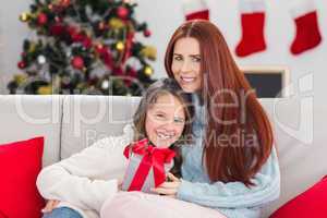 Festive mother and daughter hugging on the couch