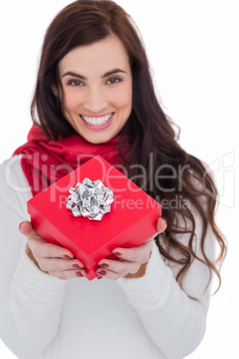 Happy brunette holding red gift with a bow
