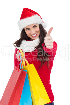 Festive brunette holding gifts and thumb up
