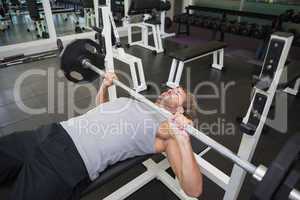 Young muscular man lifting barbell in gym