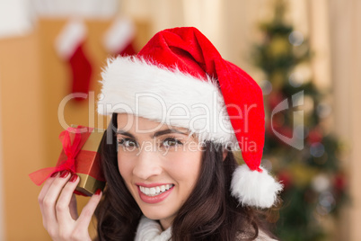Festive brunette showing gift at chistmas