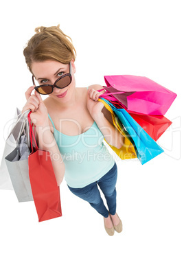 Blonde looking over her sunglasses while holding bags