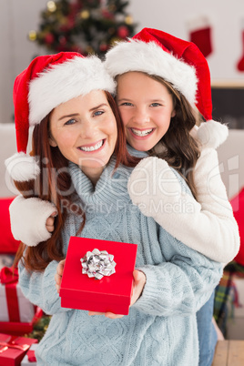 Festive mother and daughter on the couch with gift