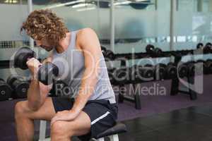 Young man exercising with dumbbell in gym