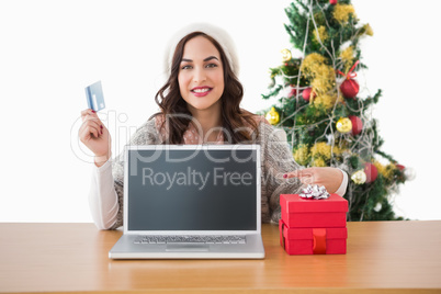 Brunette holding credit card and showing her laptop