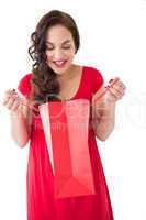 Stylish brunette in red dress opening gift bag