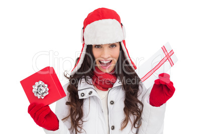 Excited brunette in winter clothes holding gifts