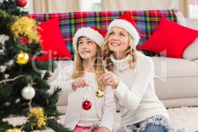 Festive mother and daughter decorating christmas tree