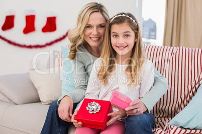 Daughter opening christmas gift with mother