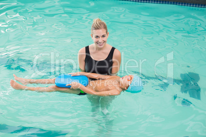 Cute little boy learning to swim with coach