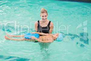 Cute little boy learning to swim with coach